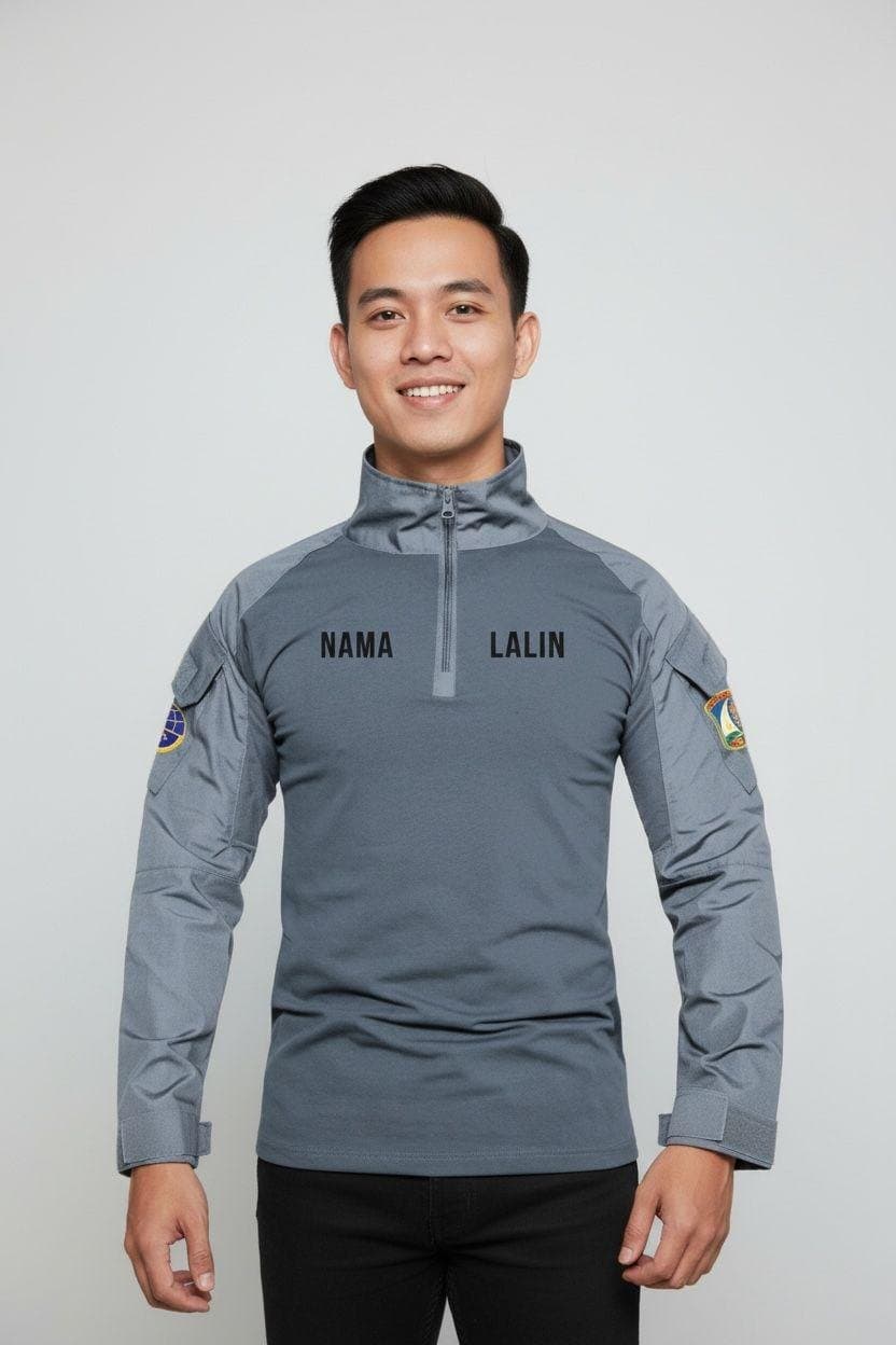 Baju lapangan abu-abu dengan papan nama dan emblem, tampak depan