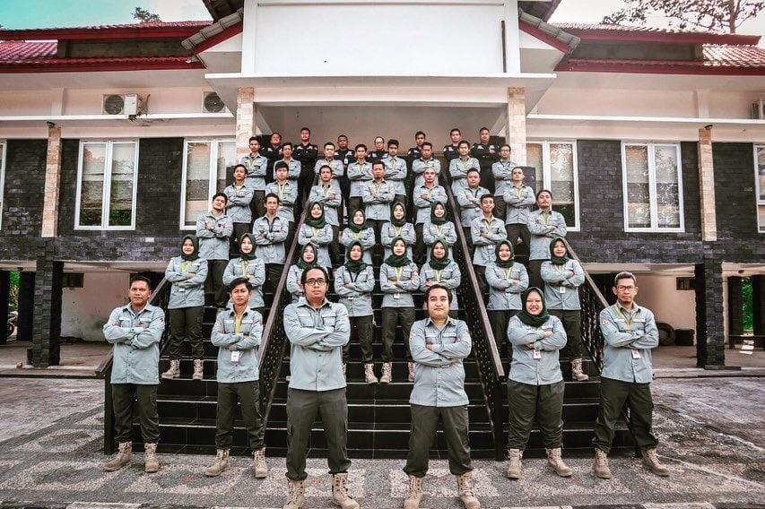 Tim berseragam kemeja abu-abu dan celana hijau berfoto bersama di depan gedung