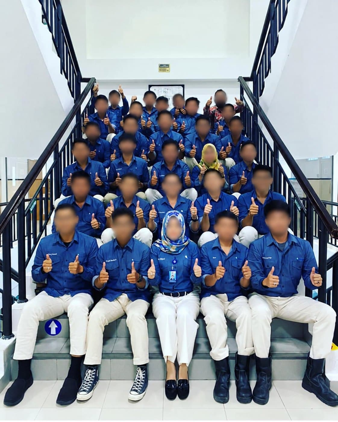 Tim berfoto bersama di tangga memakai kemeja seragam biru